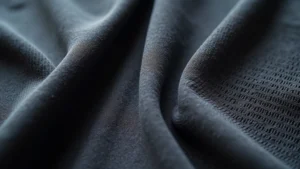 Close-up of premium athletic fabric weave showing moisture-wicking microfiber construction with visible mesh ventilation panels, photorealistic professional product photography
